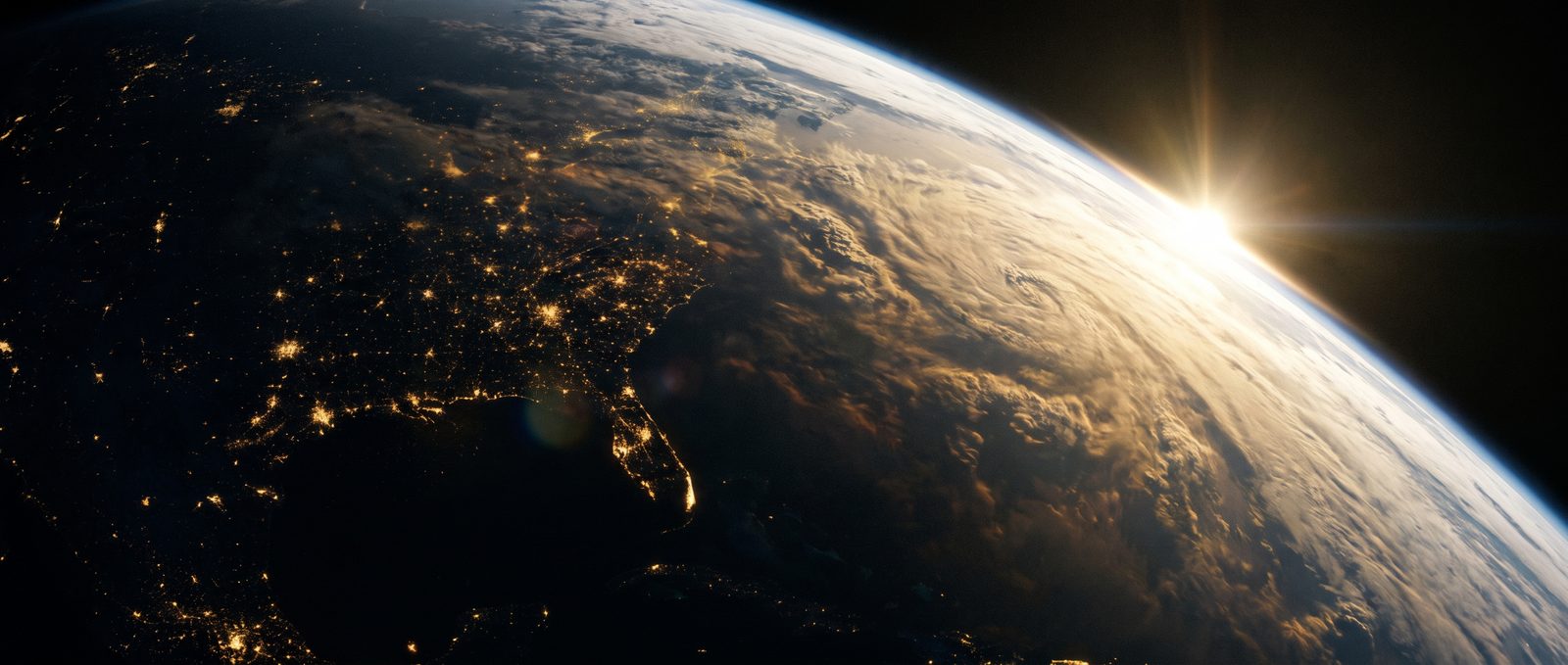The Earth at night seen from orbit, city lights scattered along the terminator